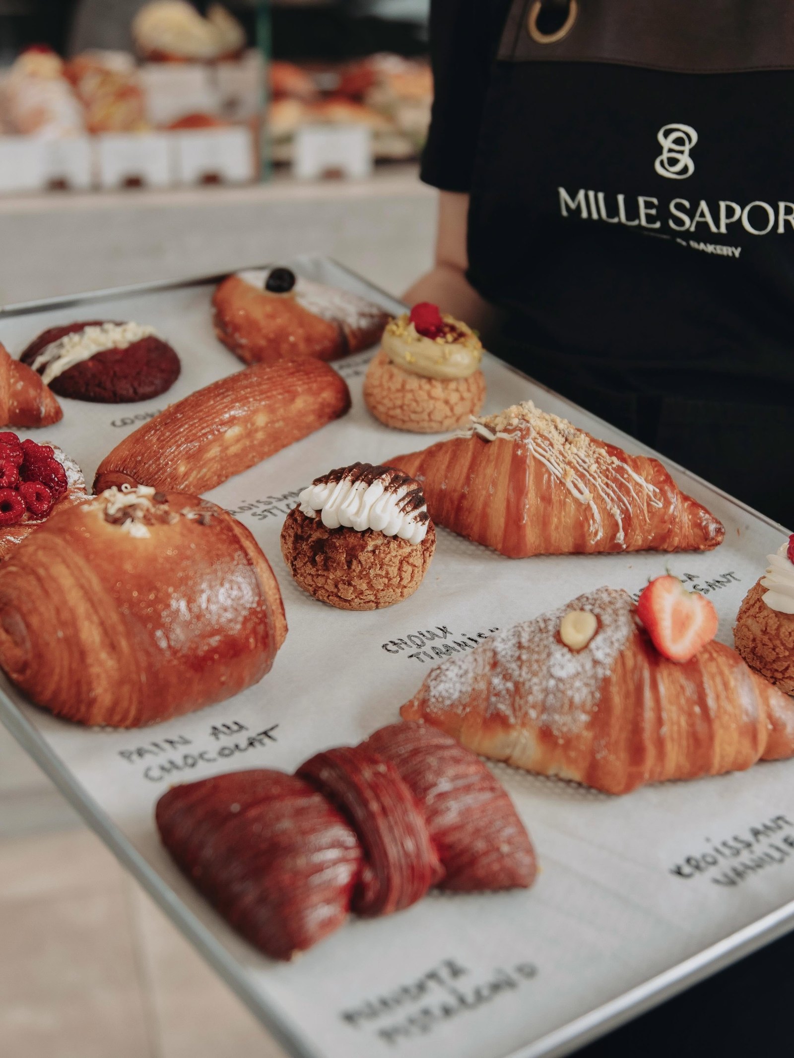 Platoul zilei la Mille Sapori — croissante, choux și danish, pe șorțul cu semnul nostru